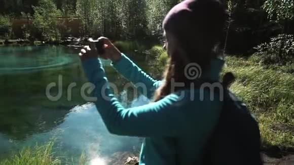 一位年轻的女游客在一个风景如画的蓝湖上用智能手机拍下了50fps的照片视频的预览图