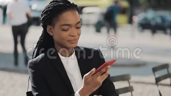 时尚的非洲商界女性在户外与手机助理通话时会用手机发送音频语音信息商务视频的预览图