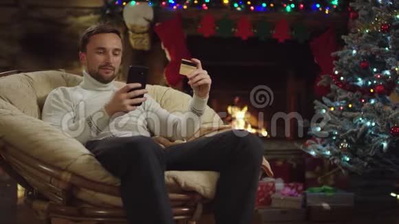 成年男子在圣诞夜通过使用智能手机和信用卡在网上购物视频的预览图