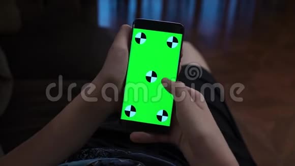 在家用智能手机帅少年的手举着一部带有垂直绿色屏幕的移动电话视频的预览图