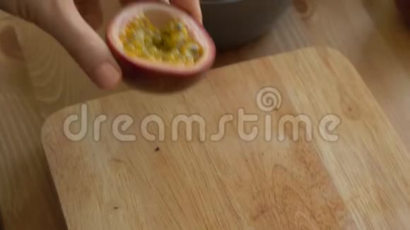 一位年轻女子用龙果和曼波方块将切好的西番莲放入碗中的慢镜头视频的预览图
