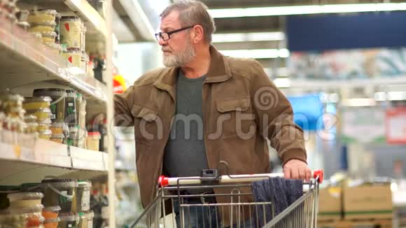 有胡子的成熟男人把胡萝卜沙拉放在超市的手推车里健康食品孤寡老人父亲节视频的预览图