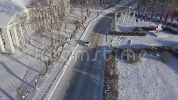 一辆孤独的白色汽车在俄罗斯一个小村庄的冬季道路上行驶的鸟瞰图库存录像美丽的霜冻视频的预览图