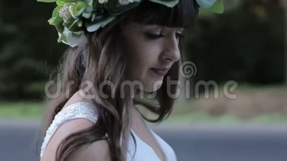 新娘头上戴绿冠独自停留在道路和森林背景上慢动作视频的预览图