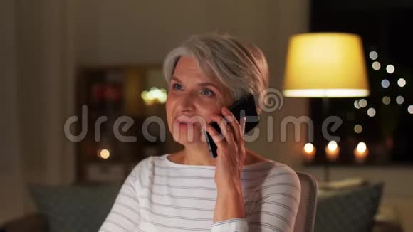 一位老太太晚上在家打智能手机视频的预览图