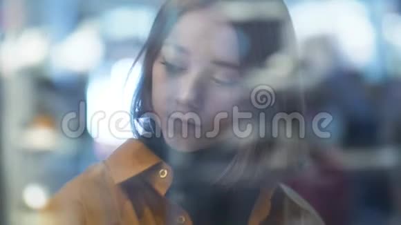 玻璃商店里一位美丽的年轻女子模糊的肖像画灯光效果视频的预览图