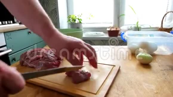 男子切鲜鱼片肉肉肉块做炒菜双手特写他在木板厨房桌子上切东西视频的预览图