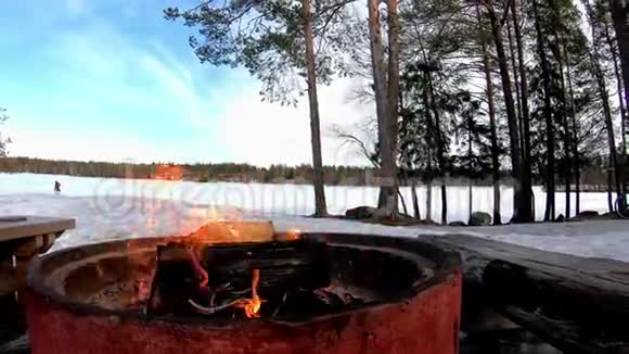 在白雪皑皑的土地上烧烤火冰封的湖泊后面有美丽的风景视频的预览图