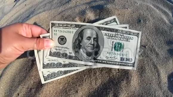 在沙滩上拿着300美元钞票的女孩视频的预览图