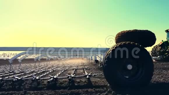 从一侧到另一侧的耕地大轮犁上的拖拉机用大金属犁耙土在上面扬起许多灰尘视频的预览图