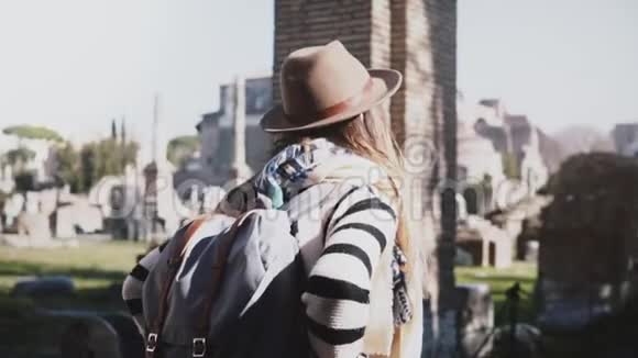 镜头围绕着年轻的旅游妇女戴着帽子背包和手臂在臀部站在意大利罗马遗址论坛视频的预览图