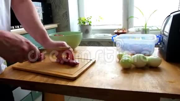 男子切鲜鱼片肉肉肉块做炒菜双手特写他在木板厨房桌子上切东西视频的预览图