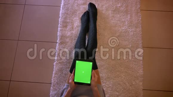 室内地毯上穿着可爱袜子的嫩嫩年轻女性的特写肖像女人在地板上敲打视频的预览图