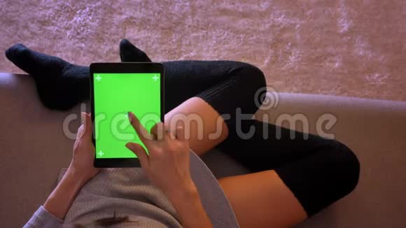 用绿色屏幕在平板电脑上使用社交媒体特写女性美容博主的肖像女孩子的双腿舒适视频的预览图