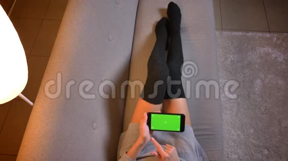 美少年网上购物的特写镜头同时使用带有绿色屏幕的手机穿着可爱袜子的女人腿视频的预览图