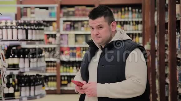 超市里的胖子在部门里喝酒看着电话视频的预览图