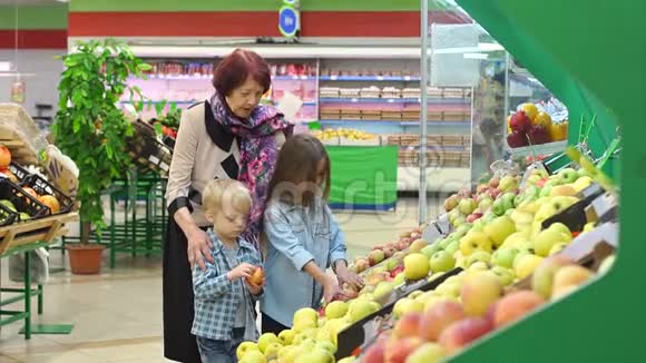 快乐的老妇人带着孙子在超市买水果视频的预览图