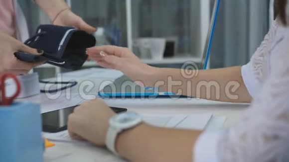 女医生测量病人在诊所办公室的压力并正在写她的任务特写视频的预览图