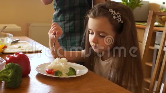 学龄前儿童在厨房吃早餐仔细咀嚼食物健康食物她妈妈旁边切沙拉视频的预览图