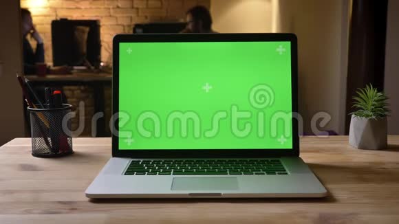 室内办公室办公桌上绿色屏幕笔记本电脑特写镜头捕捉工作场所组织视频的预览图