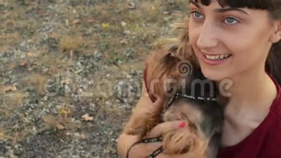 一个微笑的白种人女孩和约克郡小狗在户外摆姿势的特写镜头视频的预览图