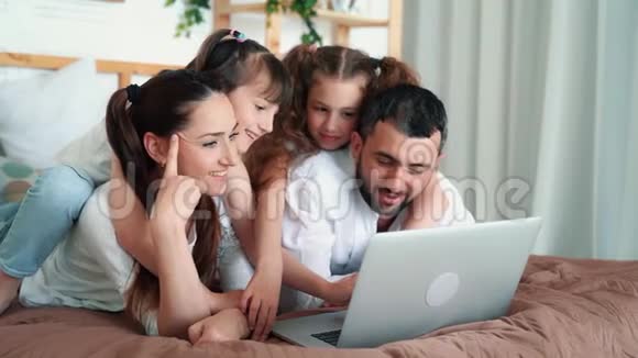 家庭幸福父母和两个女儿在笔记本电脑上看电影慢动作视频的预览图