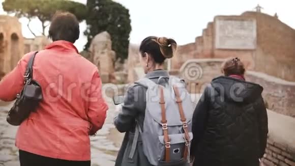 兴奋的快乐混龄欧洲旅游女性在意大利奥斯蒂亚探索古老的历史遗迹看看智能手机照片视频的预览图