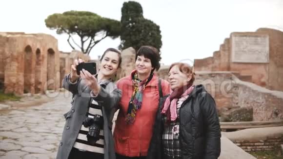 令人兴奋的高级旅游女性和微笑的欧洲年轻女孩在意大利奥斯蒂亚的古老历史遗迹附近自拍视频的预览图