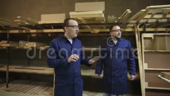 两名戴着安全护目镜的工人在家具厂散步和交谈视频的预览图