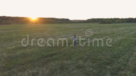 日落时分女人走在田野上手臂伸向两边视频的预览图