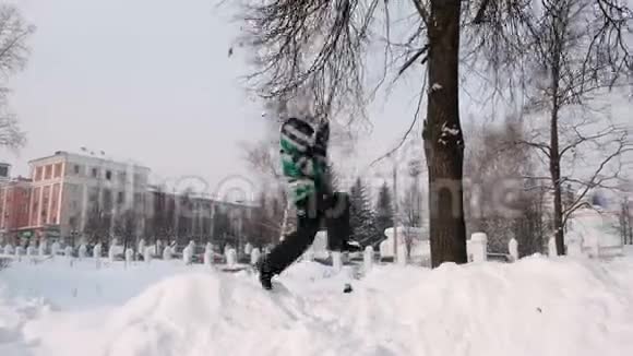 在下雪的日子里男孩在冬天的城市公园的树枝上摇摆下雪了视频的预览图