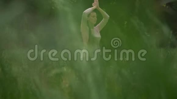 一位孕妇在公园里练习瑜伽坐在莲花的位置抱着她的手臂在上面冥想视频的预览图