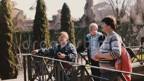 快乐的高加索族朋友站在一起在美丽的公园微笑和交谈度假罗马论坛意大利视频的预览图