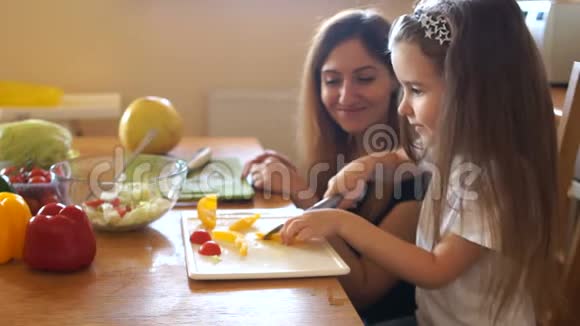 学龄前儿童自己在厨房做沙拉她妈妈在看着一边说一边尝试蔬菜视频的预览图
