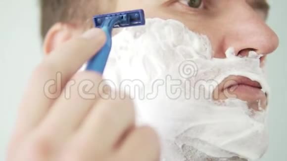 一个人用一把蓝色剃刀刮脸视频的预览图