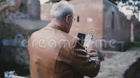 快乐的高级欧洲男人在意大利奥斯蒂亚的古镇遗址拍照退休度假之旅视频的预览图