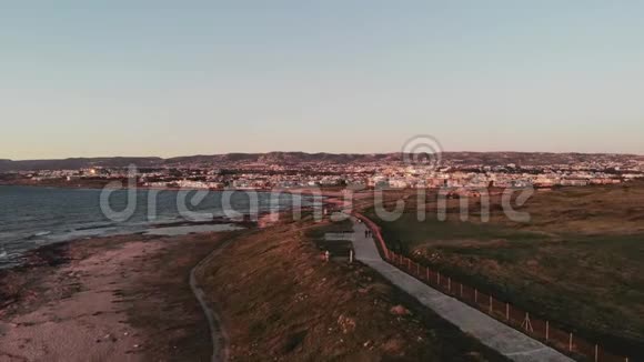 空中无人机观帕福斯城和日落地中海码头行人步行风波浪浪的大海和沿着大海的小径视频的预览图
