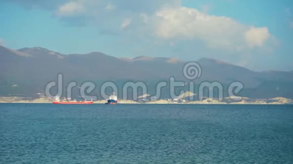 拍摄一艘货船在公海上以另一艘船为背景的运动山脉海洋和天空视频的预览图