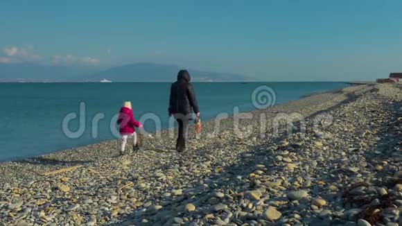 一个女人和一个小女孩在海边散步互相交谈在海边和一个女人和一个女孩交谈视频的预览图