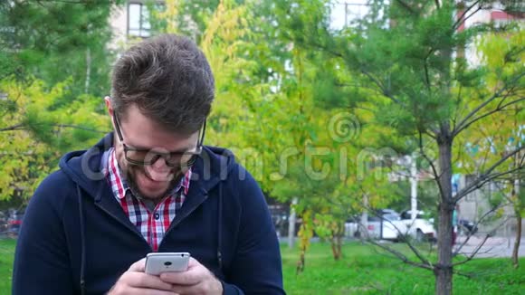一个留着胡须和眼镜的开朗的人正在公园里等着缓行视频的预览图