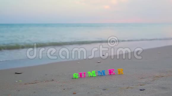 夏天从沙质海岸上的彩色塑料字母中这些字母被海浪冲走视频的预览图