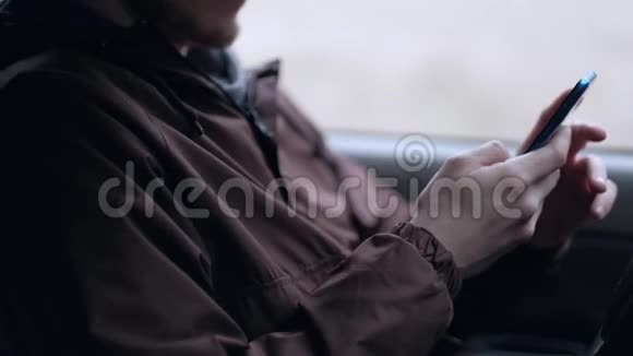 一个年轻人使用智能手机坐在汽车的船舱里视频的预览图