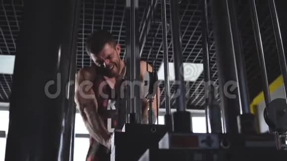 运动男子戴兜帽在健身房锻炼三头肌与下拉绳健身器材机器附件视频的预览图