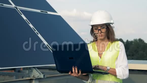 太阳能电池板和一位女工程师带着一台笔记本电脑替代能源概念视频的预览图
