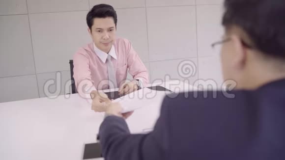 慢动作有吸引力的年轻亚洲商人在一次面试的企业人事经理谁阅读他的简历视频的预览图