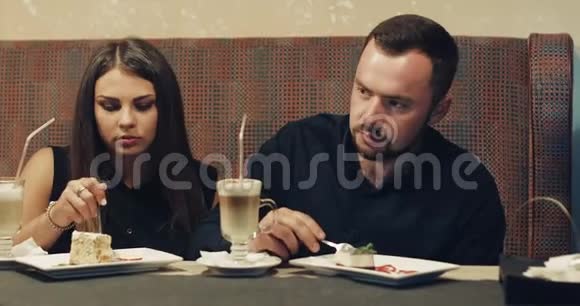 一对年轻夫妇坐在咖啡馆里用勺子互相喂一个美味的蛋糕A视频的预览图
