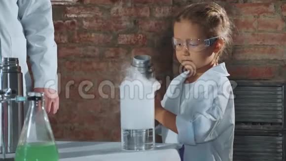 儿童科学家从烧杯中的钢制热水瓶中注入液氮视频的预览图