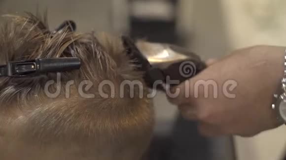 儿童发型师在美发沙龙用电动剃须刀切割小男孩海丽丝师做儿童发型视频的预览图