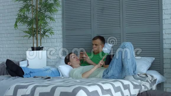有数字设备的情侣在床上放松视频的预览图