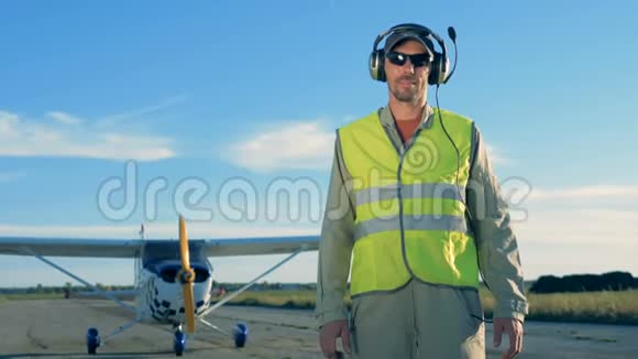 飞行员站在飞机背景上带耳机的人站在起飞跑道上视频的预览图